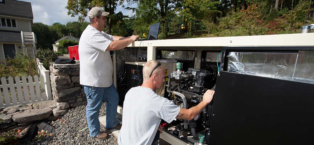 Two Gen Plus technicians working on a large generator